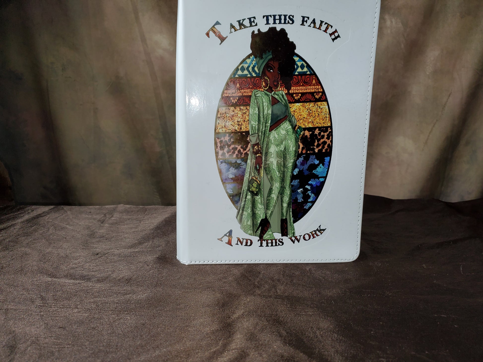 White Leatherette Journal with a picture of a woman in a Fancy green outfit with the words "Take This Faith and This Work"