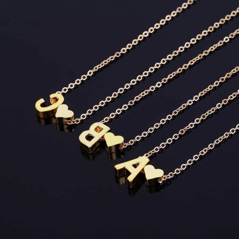 gold colored necklace with heart and letter initial charm